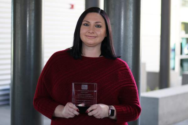 A photo of Alicia Hallex posing with an award.