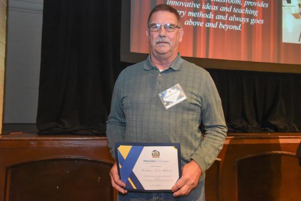 A photo of Berchman Melancon holding an excellence award