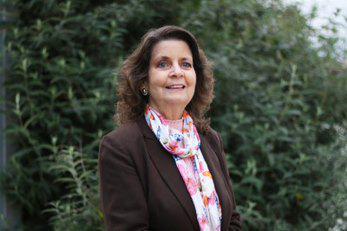 A photo of Patricia Jenkins standing in front of some foliage. 