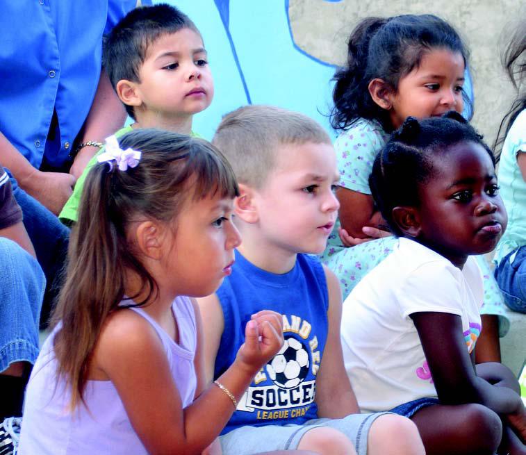 A photo of children sitting and listening